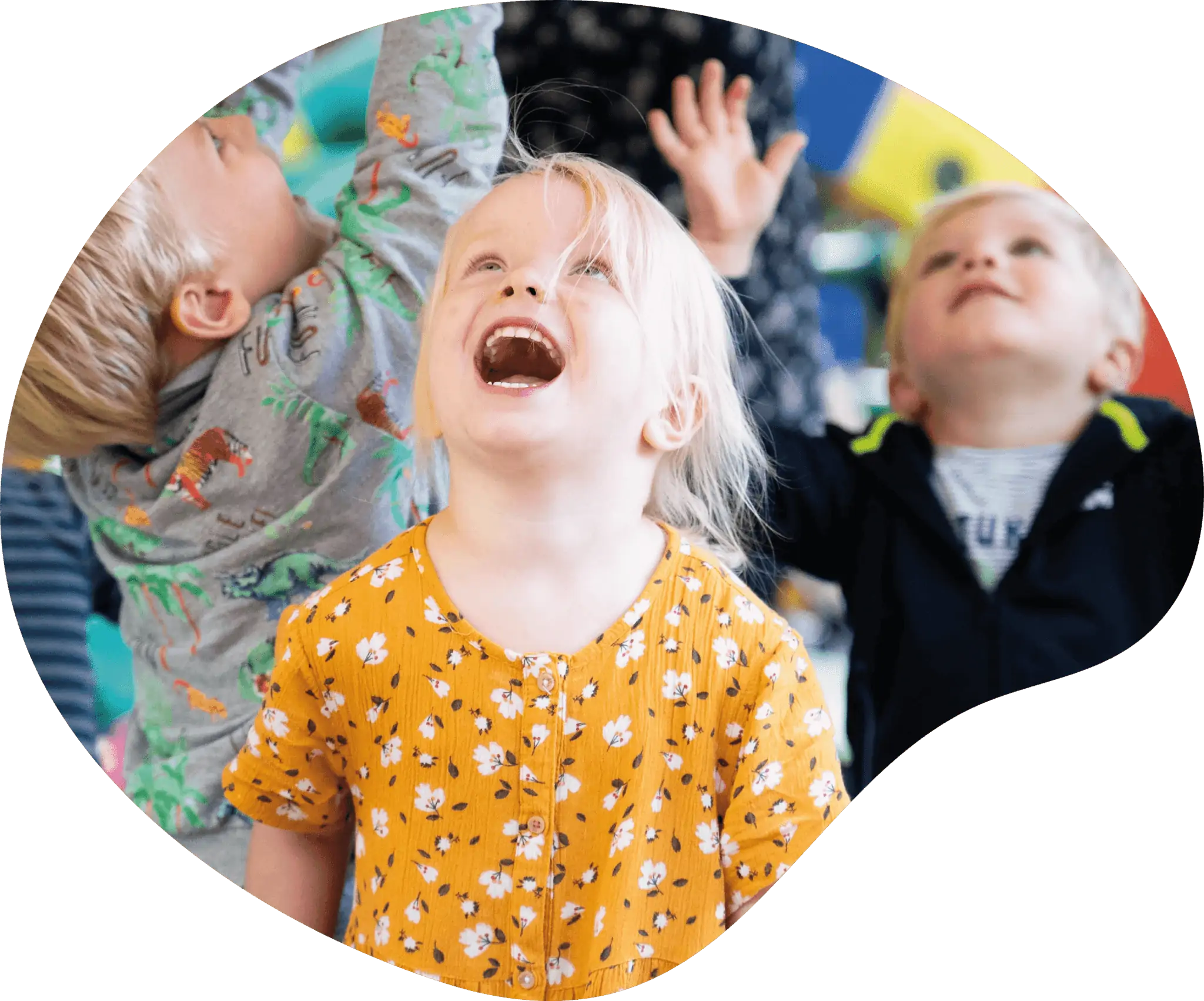 Drie kinderen kijken lachend omhoog tijdens het spelen bij Poespas